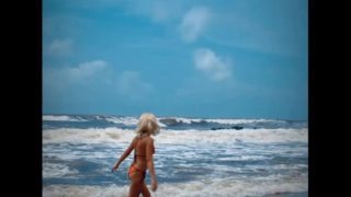 Tik Tok. Beach Voyeur looks on Blonde Teen enjoying Topless in the waves. 