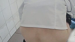 White lady in black pants and white blouse pissing in the toilet