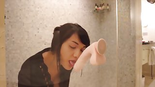 Super hot babe sucks and fucks a dildo attached to a glass shower door.