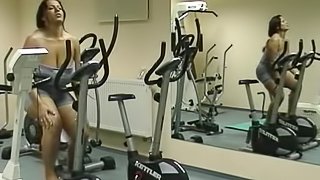 Solo brunette with big natural tits exercising passionately in the gym
