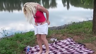 Blonde beauty plays with her twat in the middle of a field