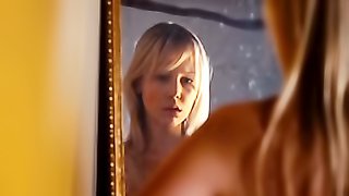 Caucasian lady touches her boobs while staring in front of the mirror.