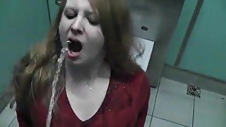 Rothaarige Freundin trinkt Urin in einer öffentlichen Toilette