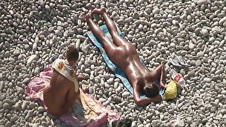 Adorable bronze skin shiny brunette sunbathing on the beach nude