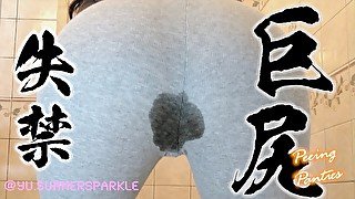 A Japanese Big Ass MILF peeing in a plastic basin while wearing gray leggings.