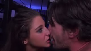 A brunette is kissed by her lover in a dark room in this scene