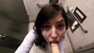 Naughty amateur teen deepthroats a dildo in a public toilet