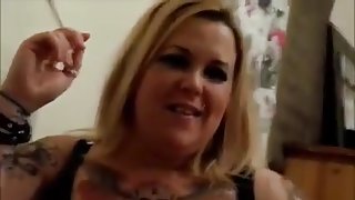 Tattooed blonde smokes cigarette and sucks penis