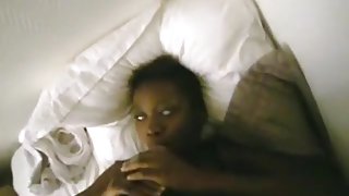 Ebony american girl lies down on the bed, while sucking cock.