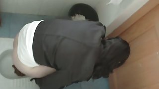 an Asian chick wearing glasses pissing in the public toilet