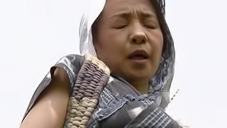 Mature Asian woman with big tits enjoying a hardcore fuck in a field