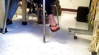 Girl dangling flip flops in class