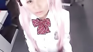 Cute Japanese babe sits down and displays her sexy body wearing her pink wig and white and black school uniform.