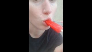 Licking a cherry popsicle on a hot summer day