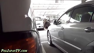 Japanase hoe takes a piss between two cars in public